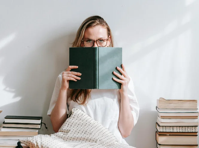 Personne tenant un livre devant son visage, illustrant une réflexion sur le coaching professionnel et le développement personnel.